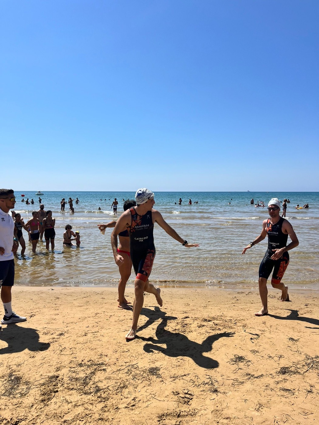 Atleti escono dall'acqua e corrono sulla spiaggia durante un aquathlon