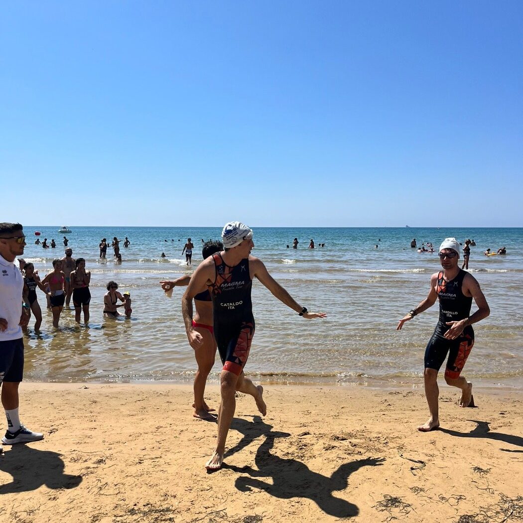 Atleti escono dall'acqua e corrono sulla spiaggia durante un aquathlon