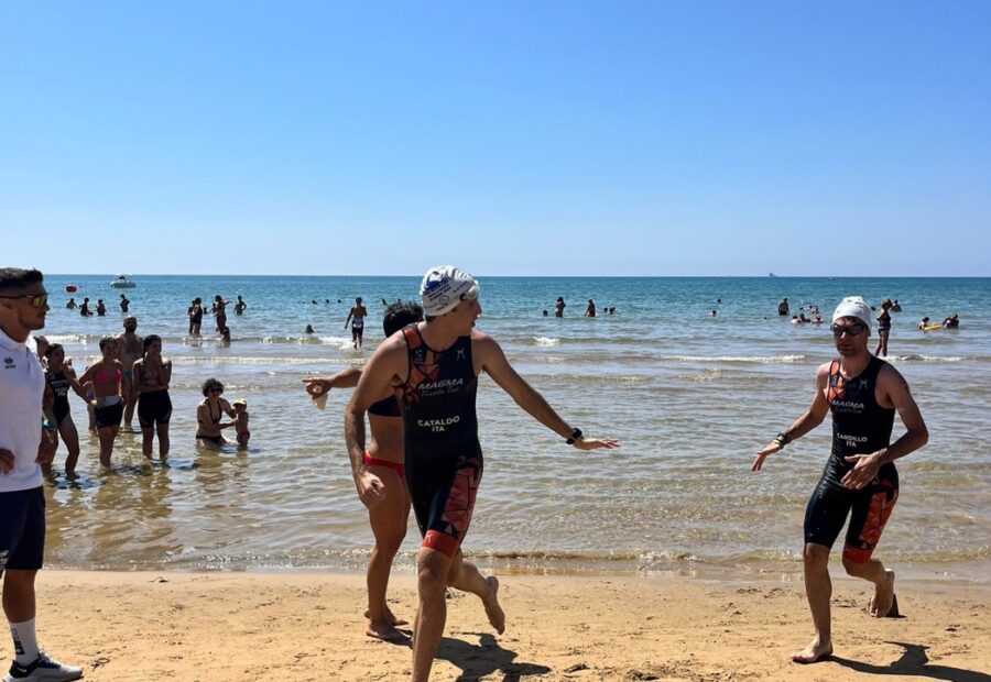 Atleti escono dall'acqua e corrono sulla spiaggia durante un aquathlon